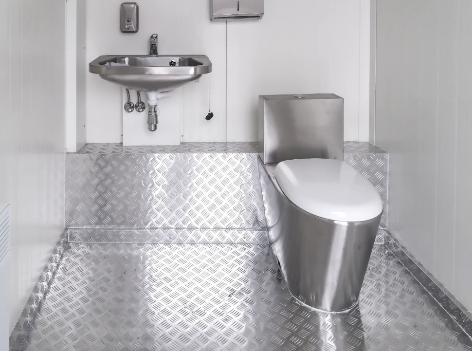 Interiör av container-WC med rostfri inredning och durk